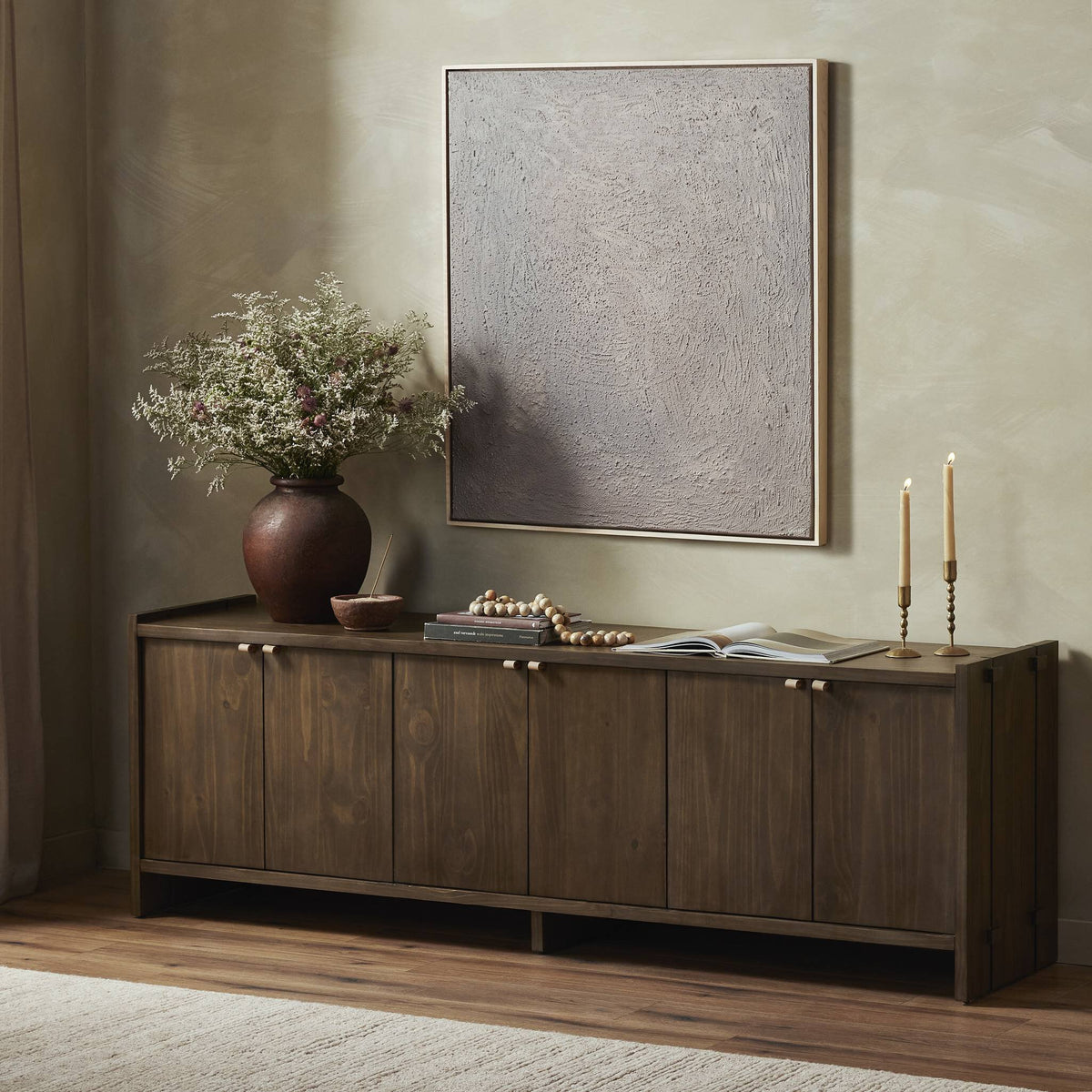 a wooden cabinet with a vase of flowers and a framed picture on the wall