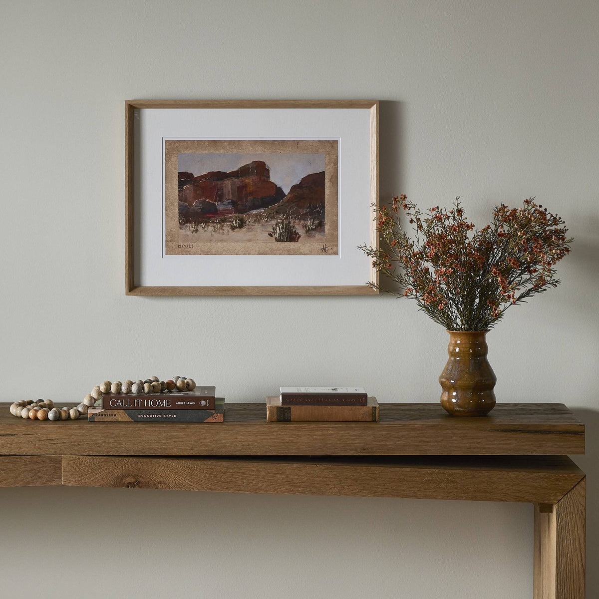 a table with a vase of flowers and a picture on the wall