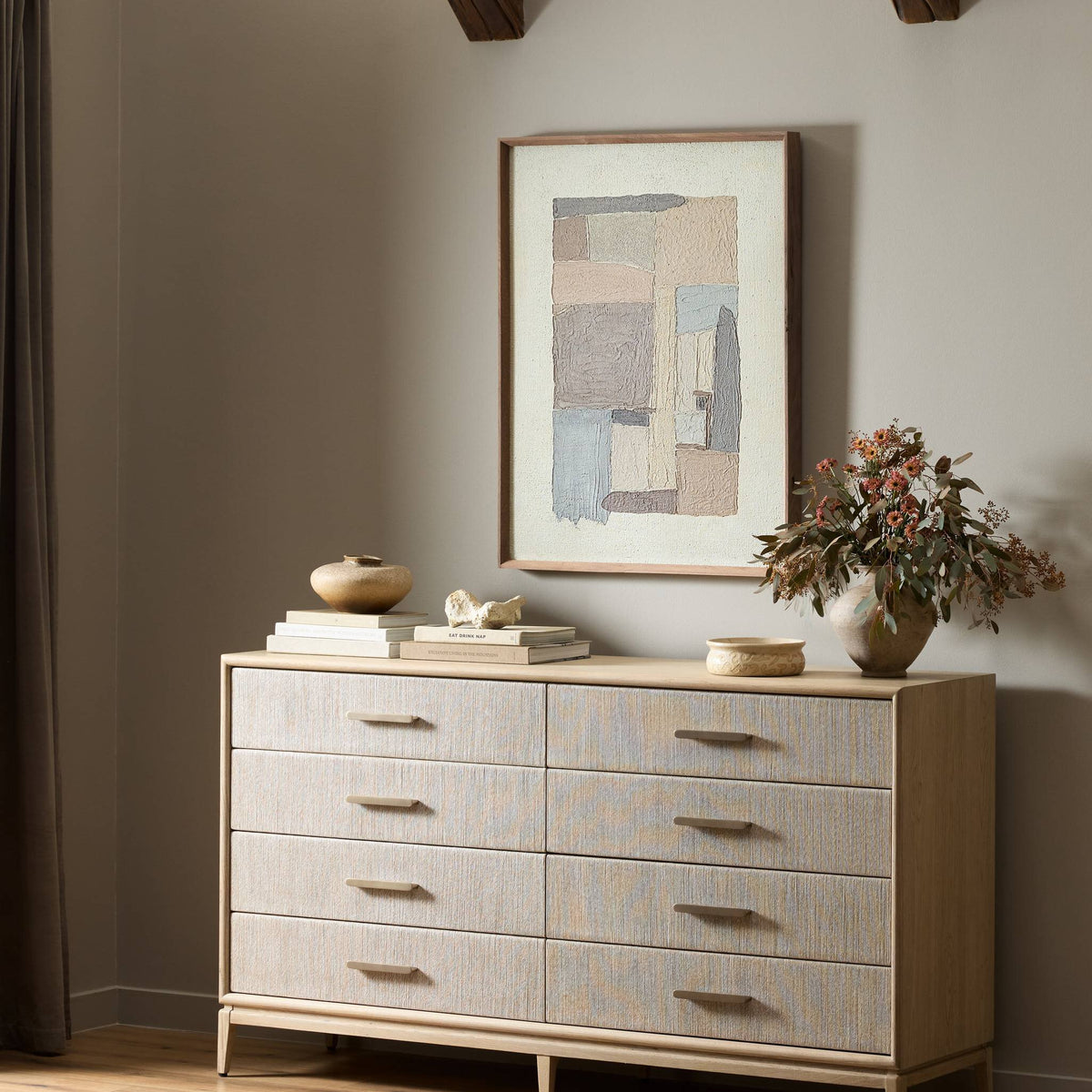 a dresser with a painting on the wall