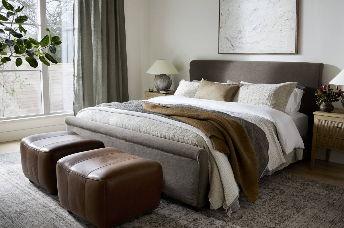 a bed with a bed and two brown ottoman