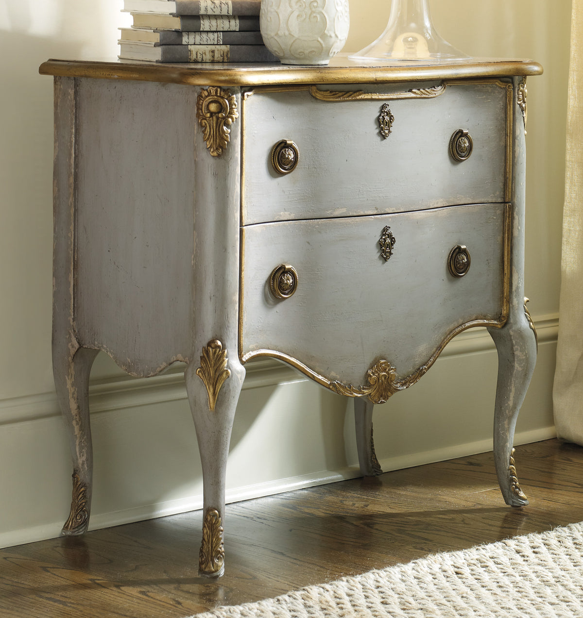 a white and gold dresser with books and vase on top
