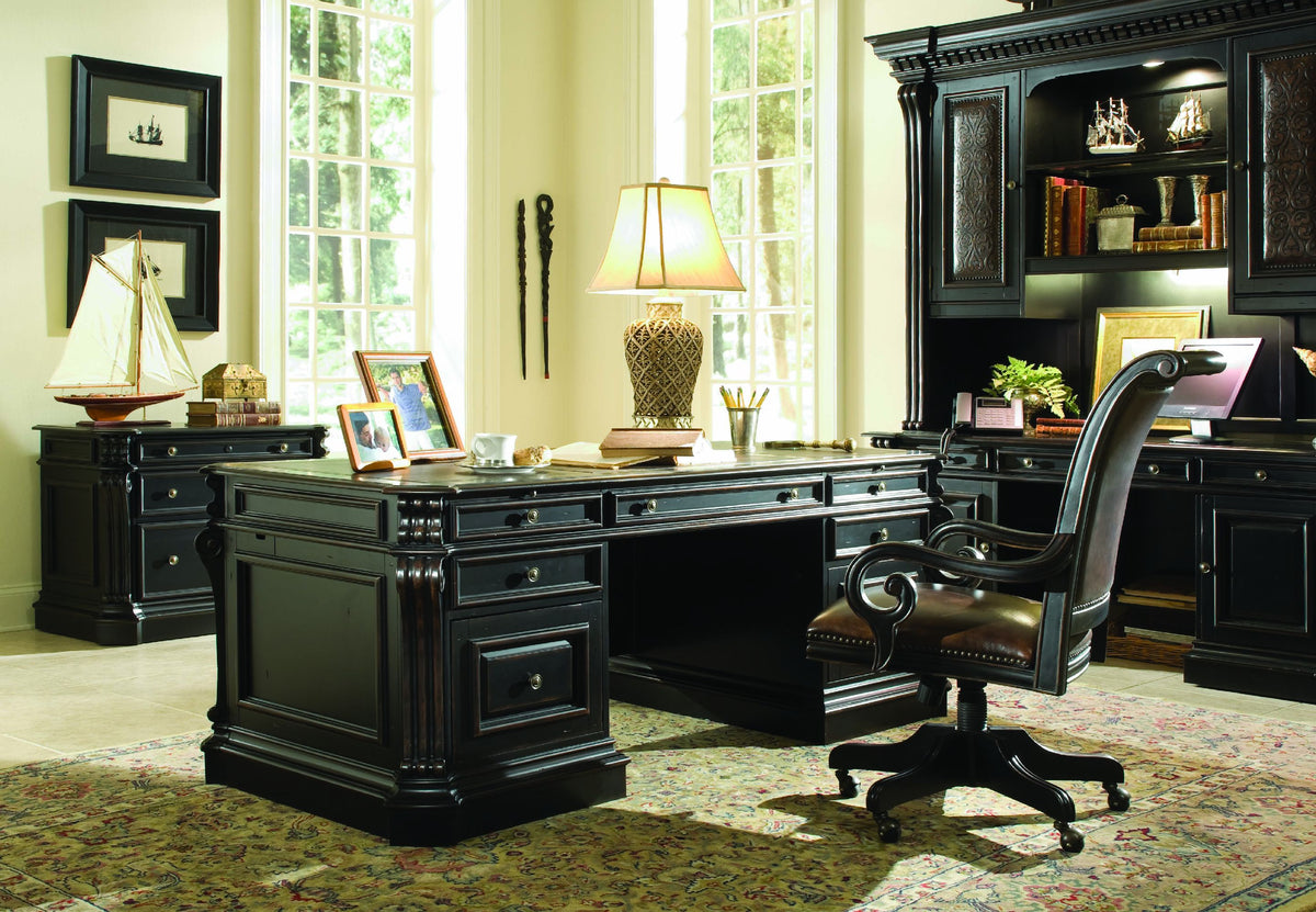a desk in a room with a lamp and bookshelf