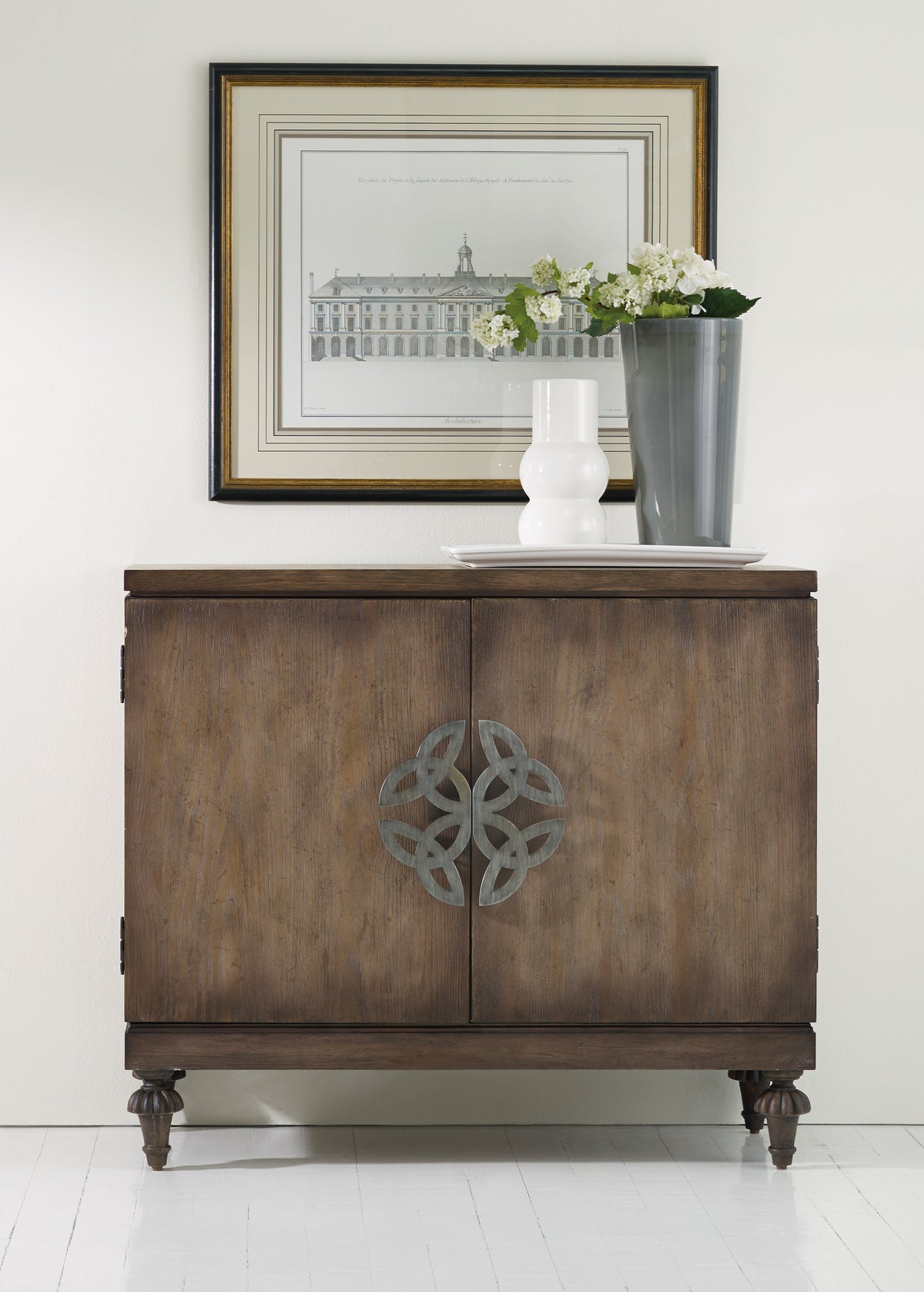 a cabinet with a vase of flowers and a picture on the wall