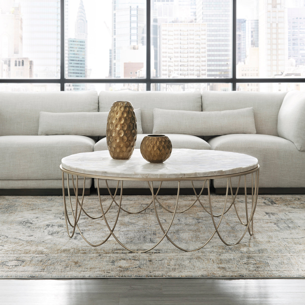 a white couch with a gold table and two vases on it