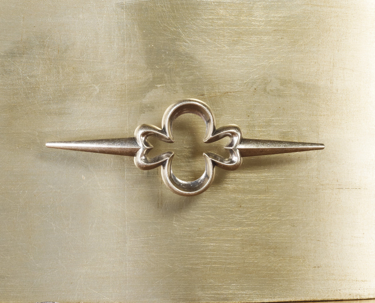 a silver object with a flower in the middle