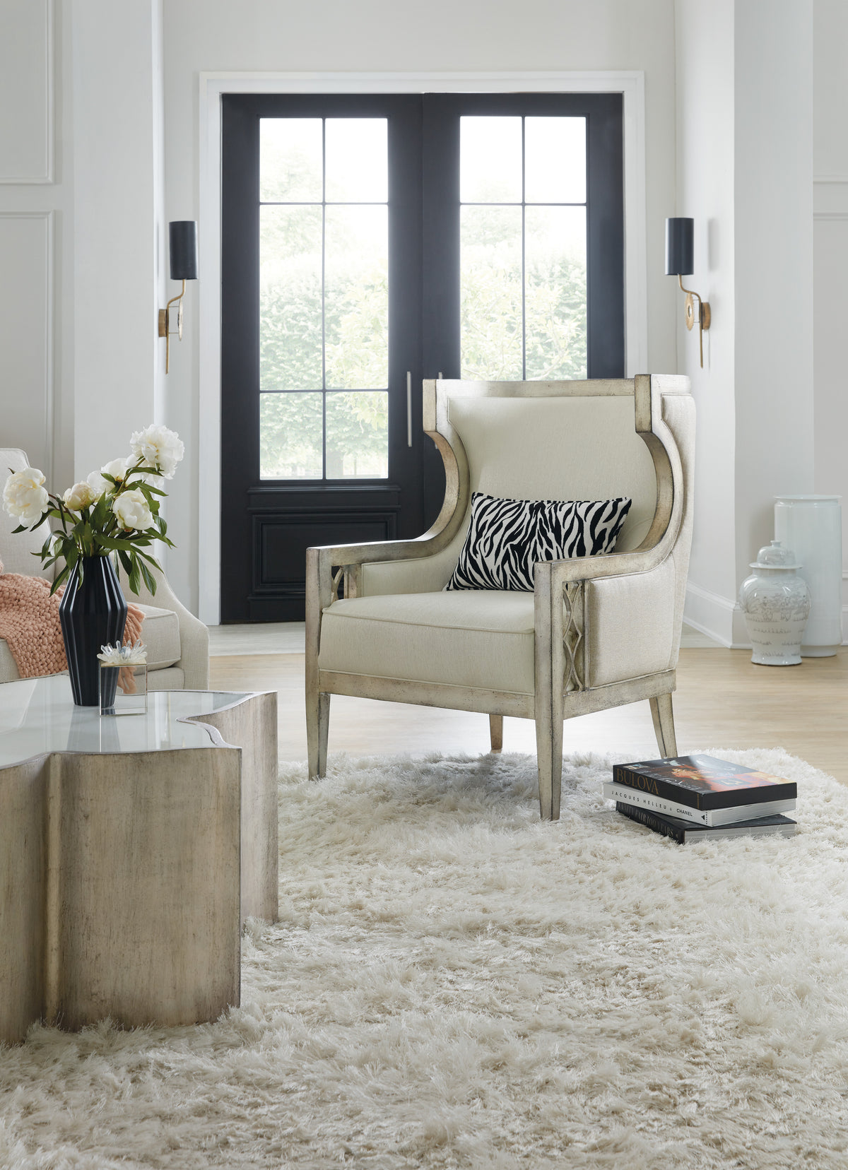 a white chair in a room with a rug and a vase of flowers