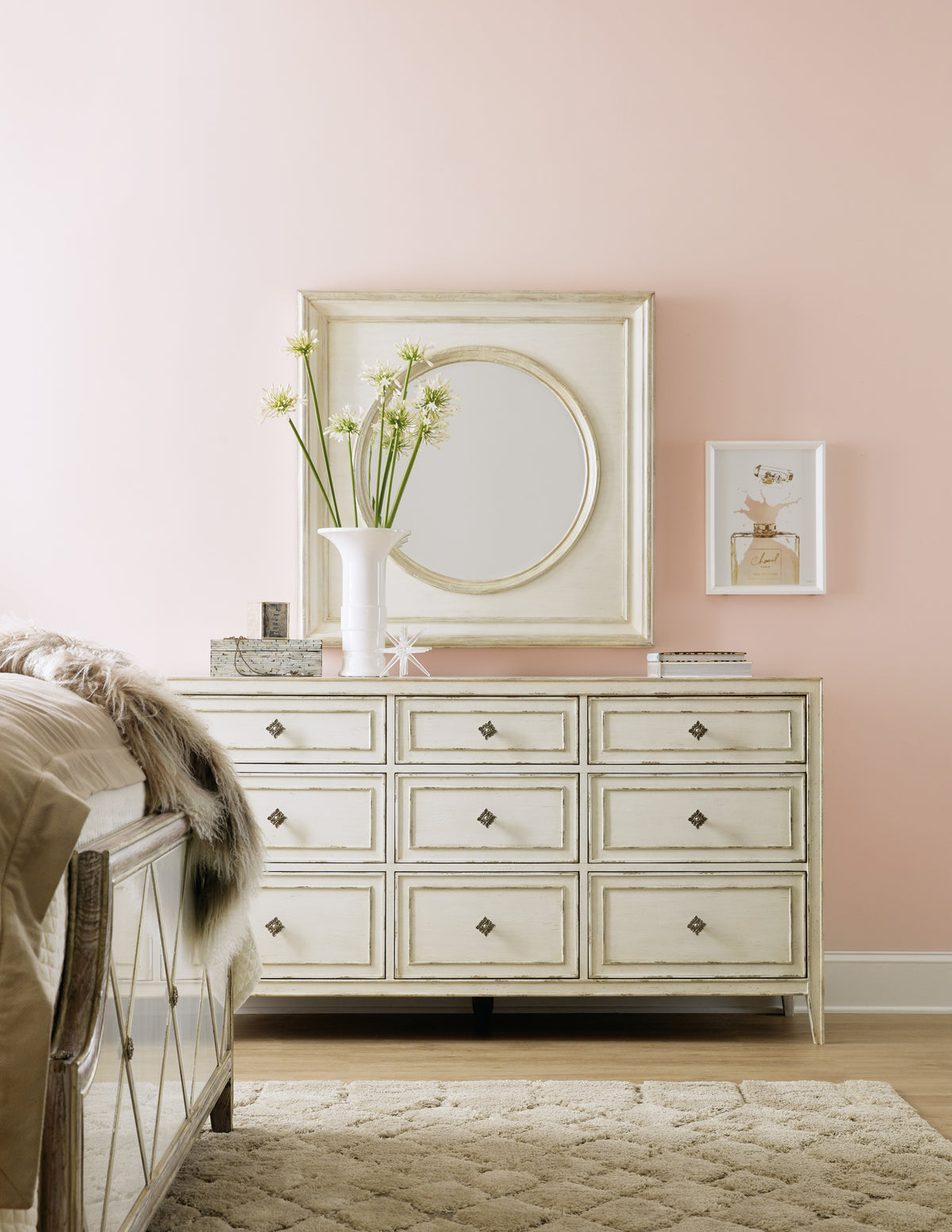 a white dresser with a mirror and a vase of flowers on top