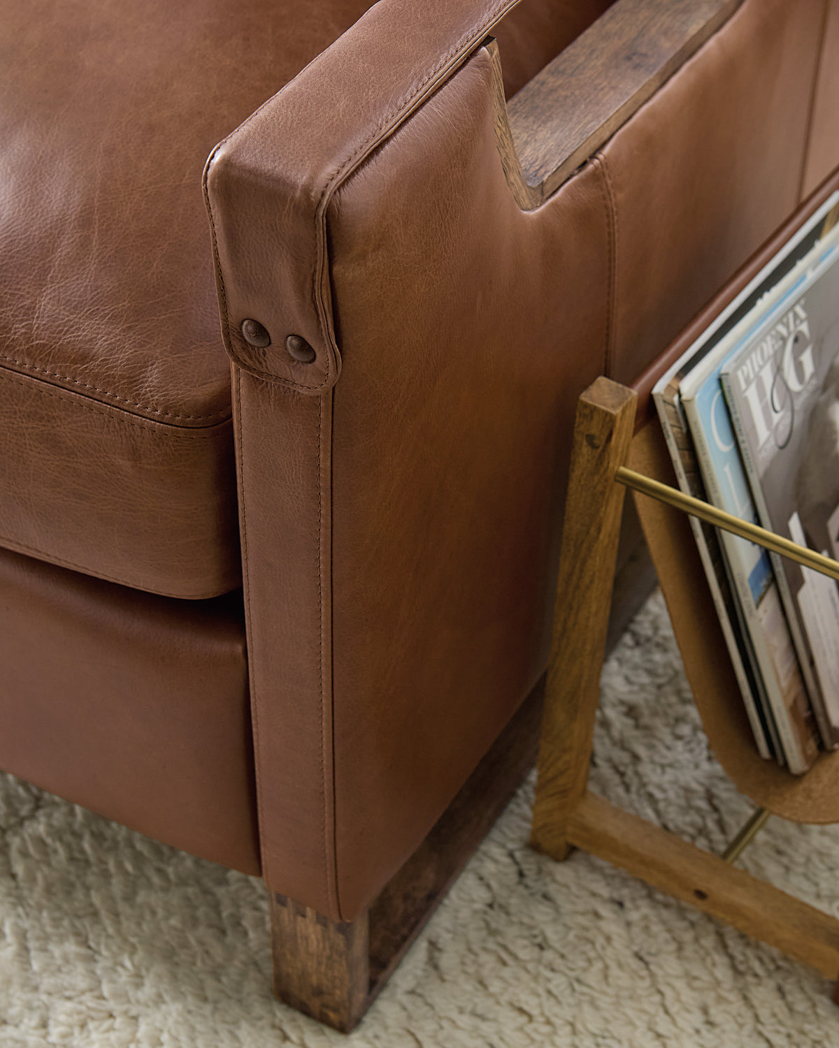 a brown leather couch next to a magazine rack