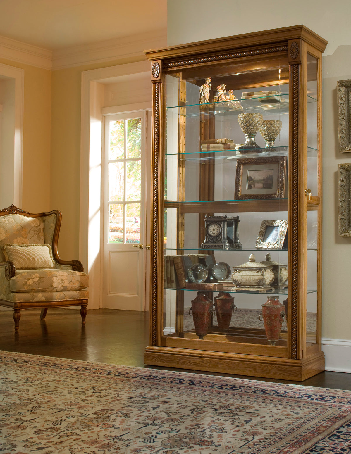 a glass cabinet with a chair and a rug