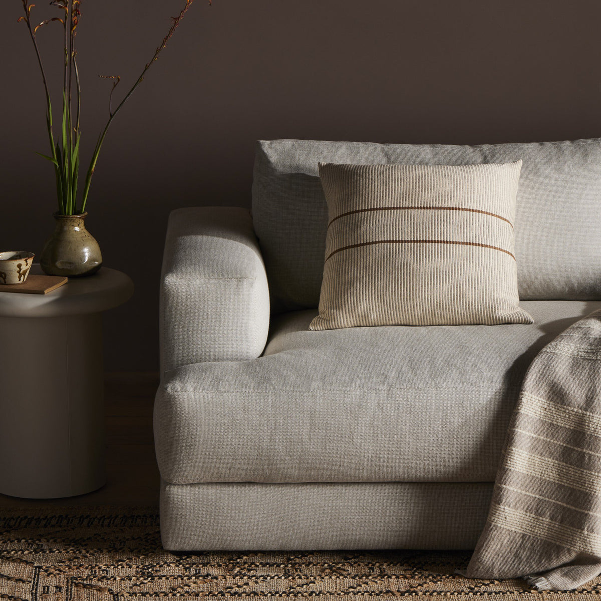 a couch with a blanket and a vase of flowers