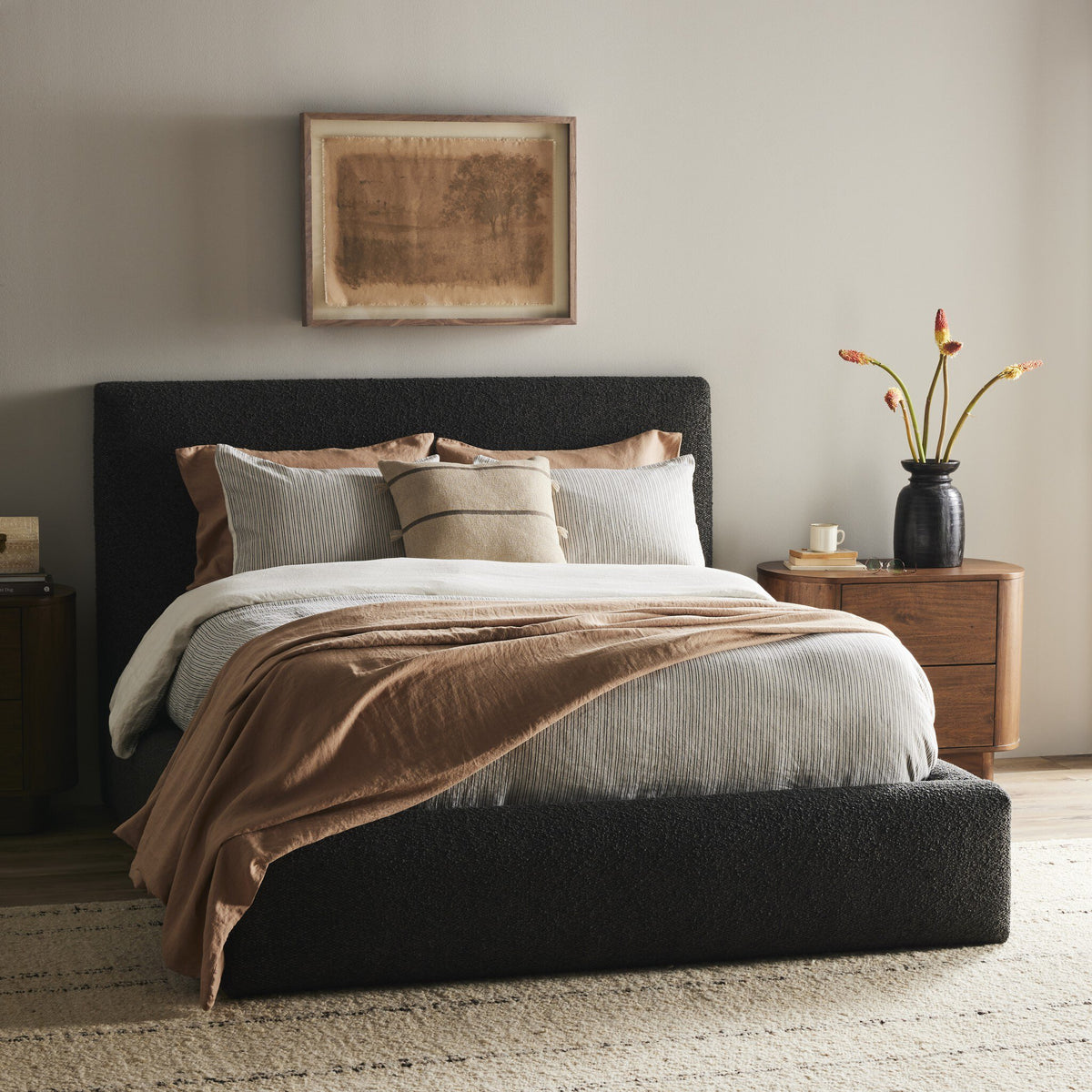 a bed with a black headboard and brown blanket