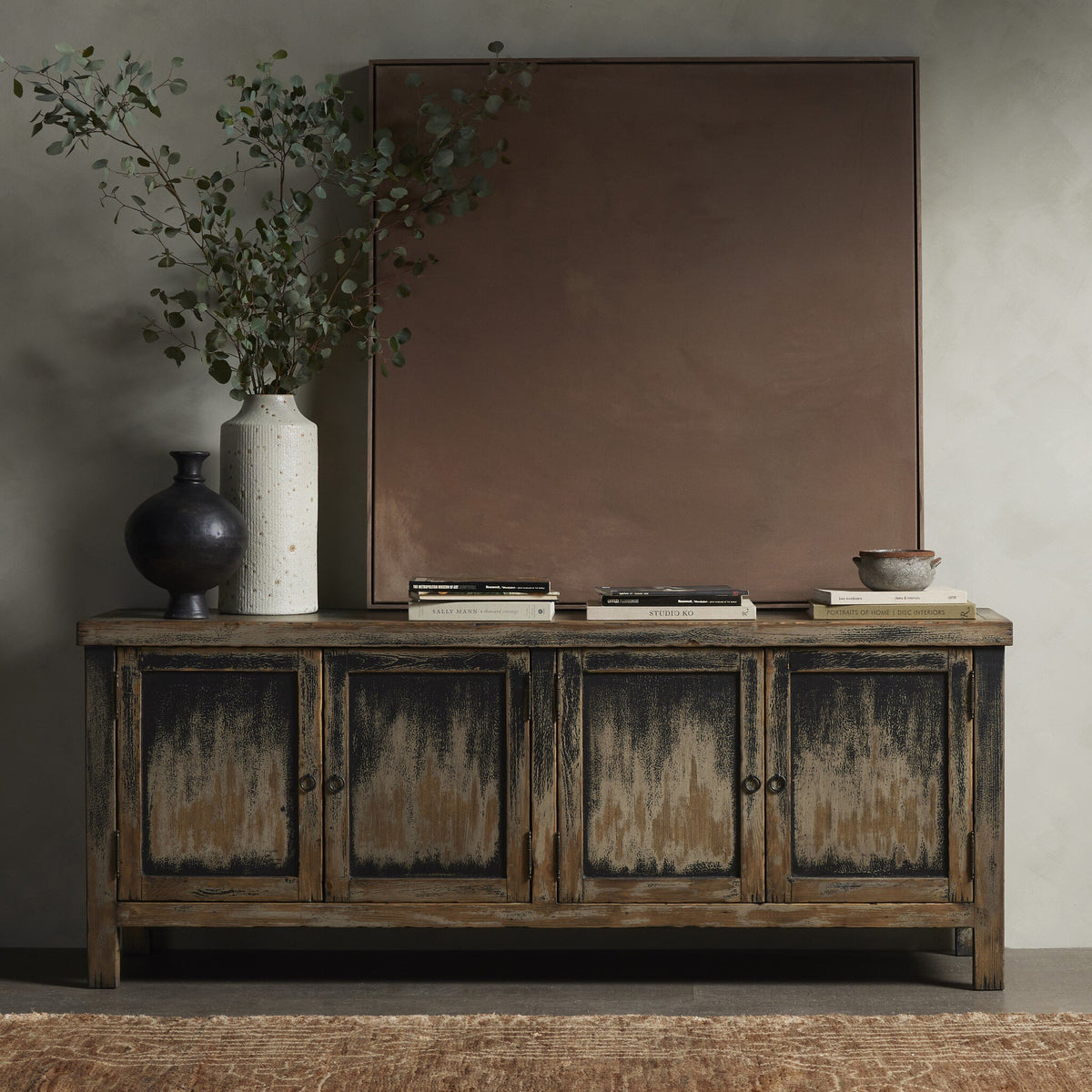 a cabinet with a plant and a painting on the wall