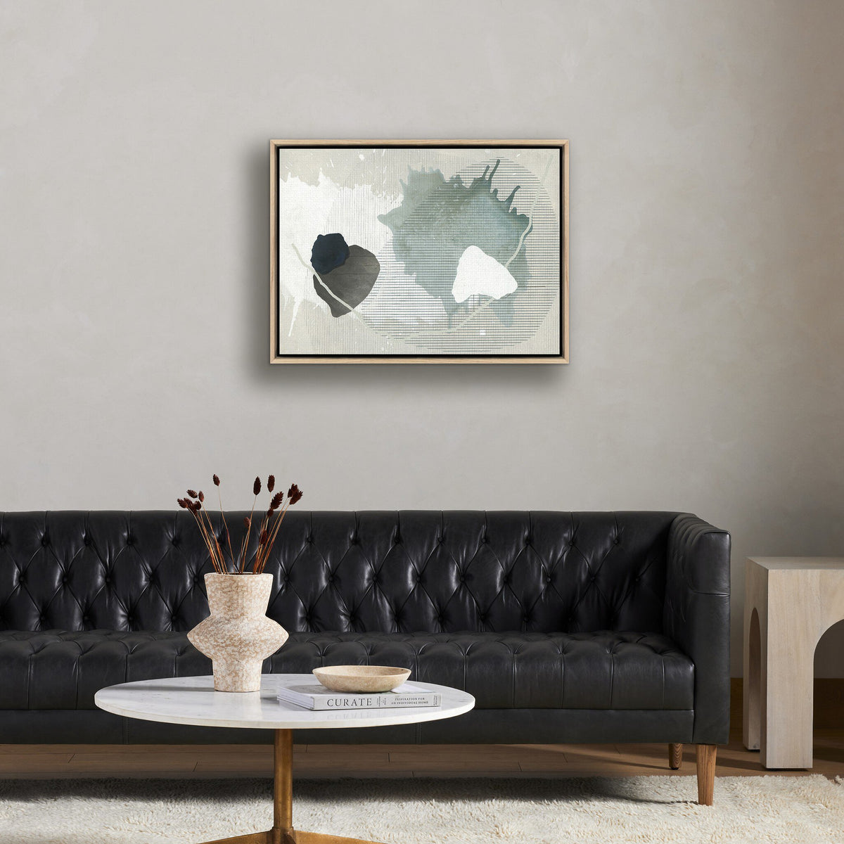 a black couch with a white coffee table and a painting on the wall