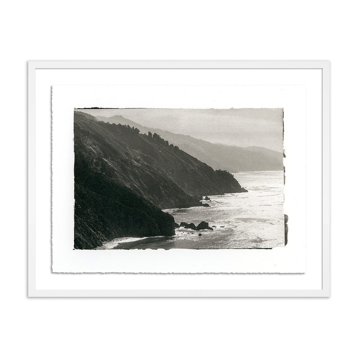 a framed picture of a cliff and water