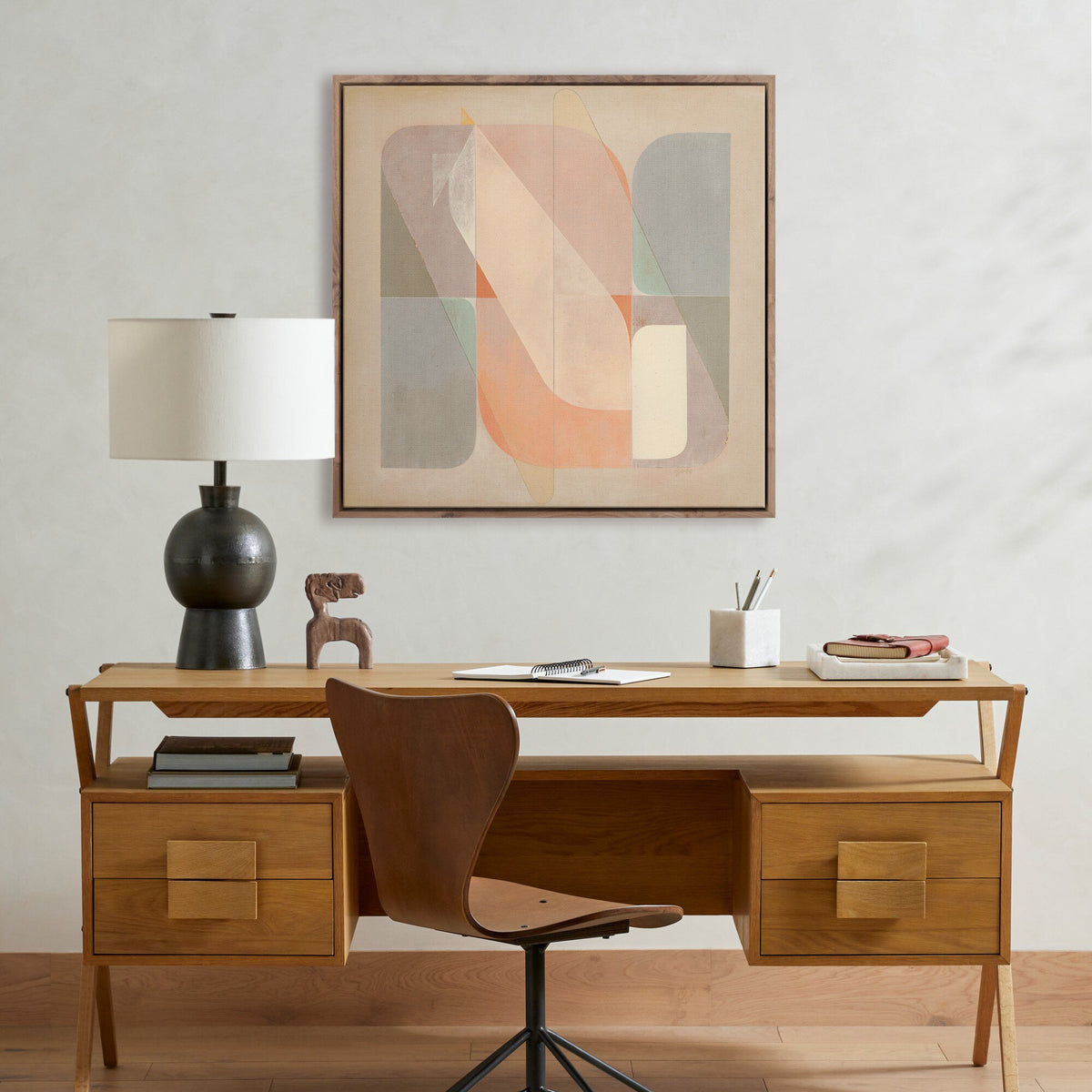 a desk with a lamp and a painting on the wall