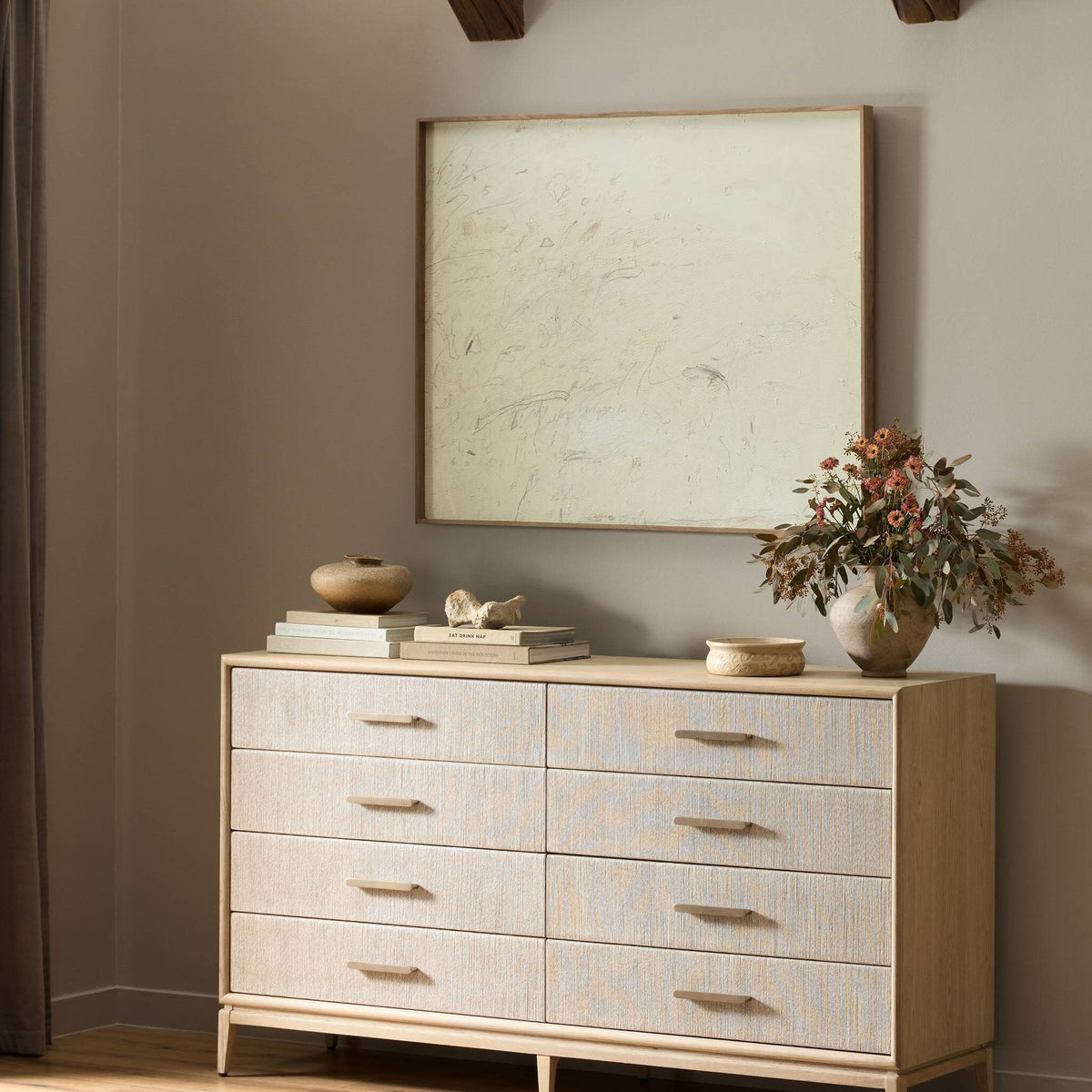 a dresser with a plant and a painting on the wall