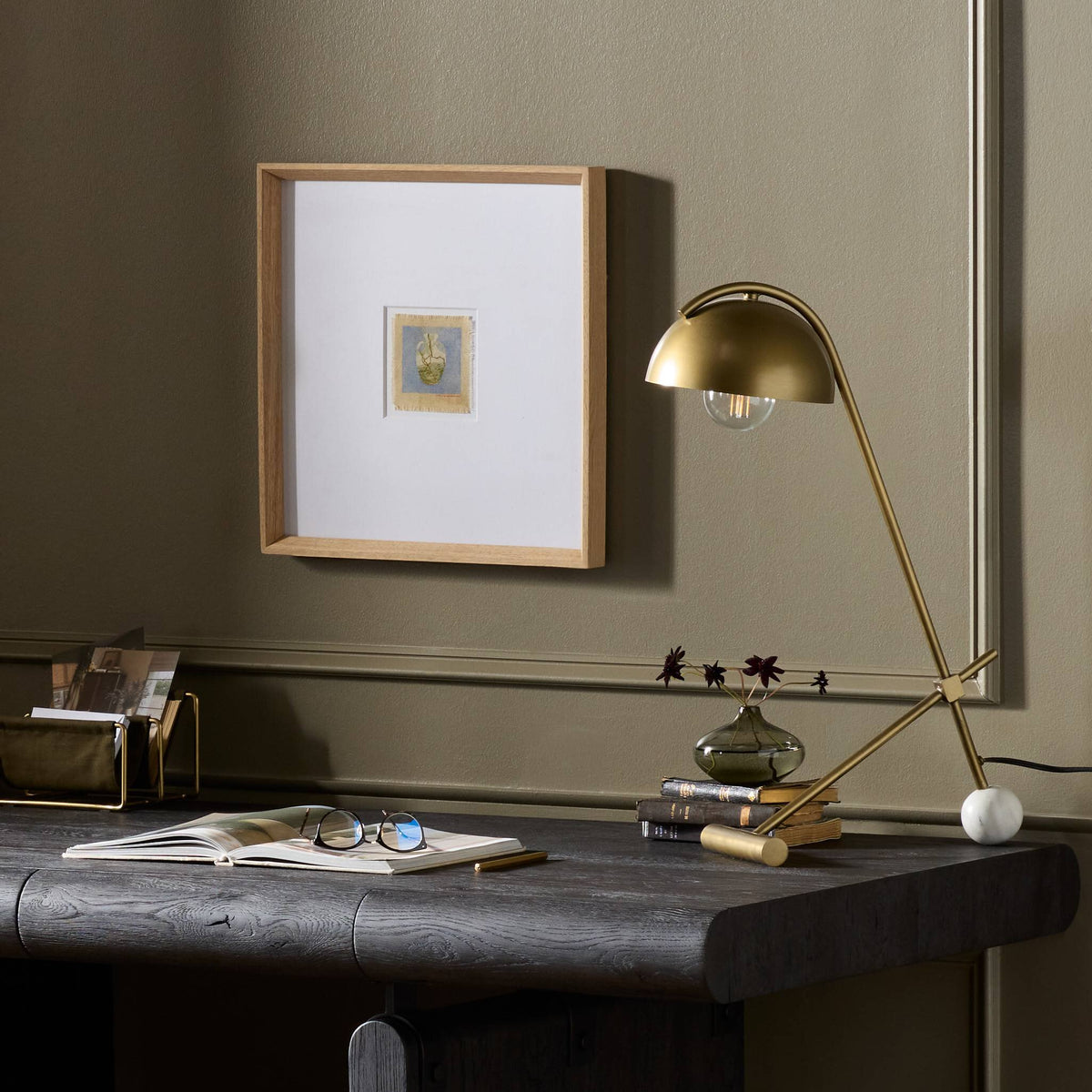 a desk with a lamp and a picture on the wall