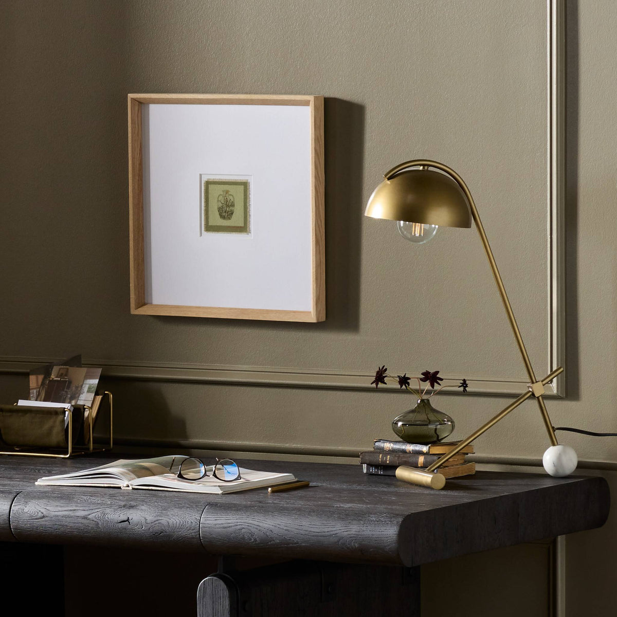 a desk with a lamp and a picture on the wall