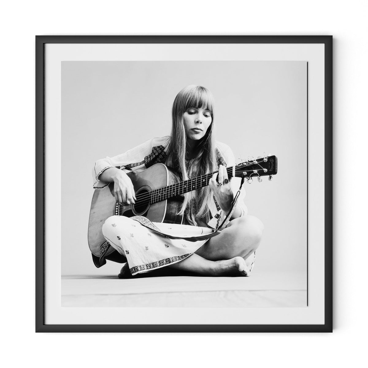 a woman sitting on the floor playing guitar
