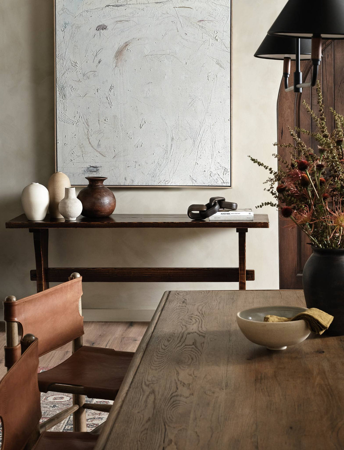 a table with a vase of flowers and a painting on the wall
