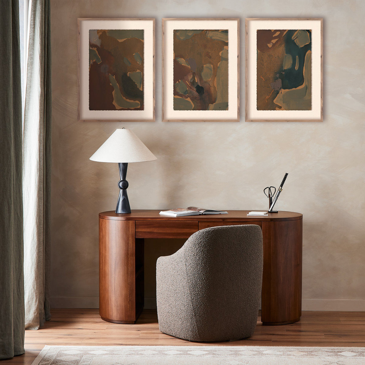 a desk with a lamp and a chair in front of a painting