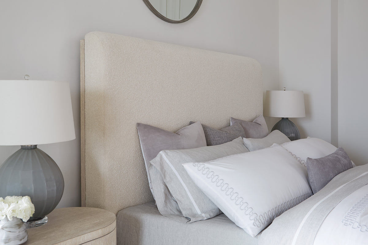 a bed with pillows and a round mirror above it
