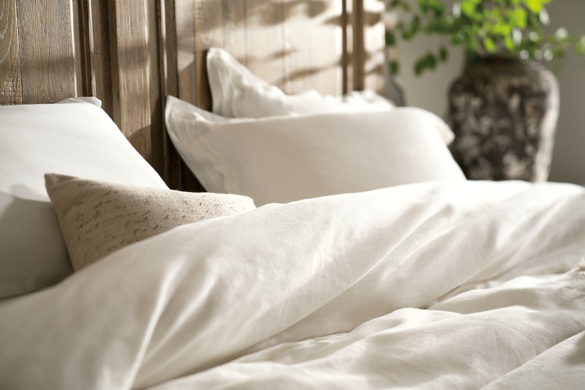 a bed with white sheets and pillows