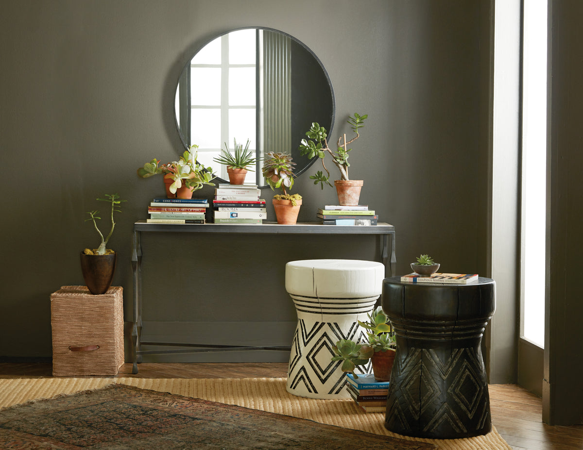 a room with a round mirror and a table with plants