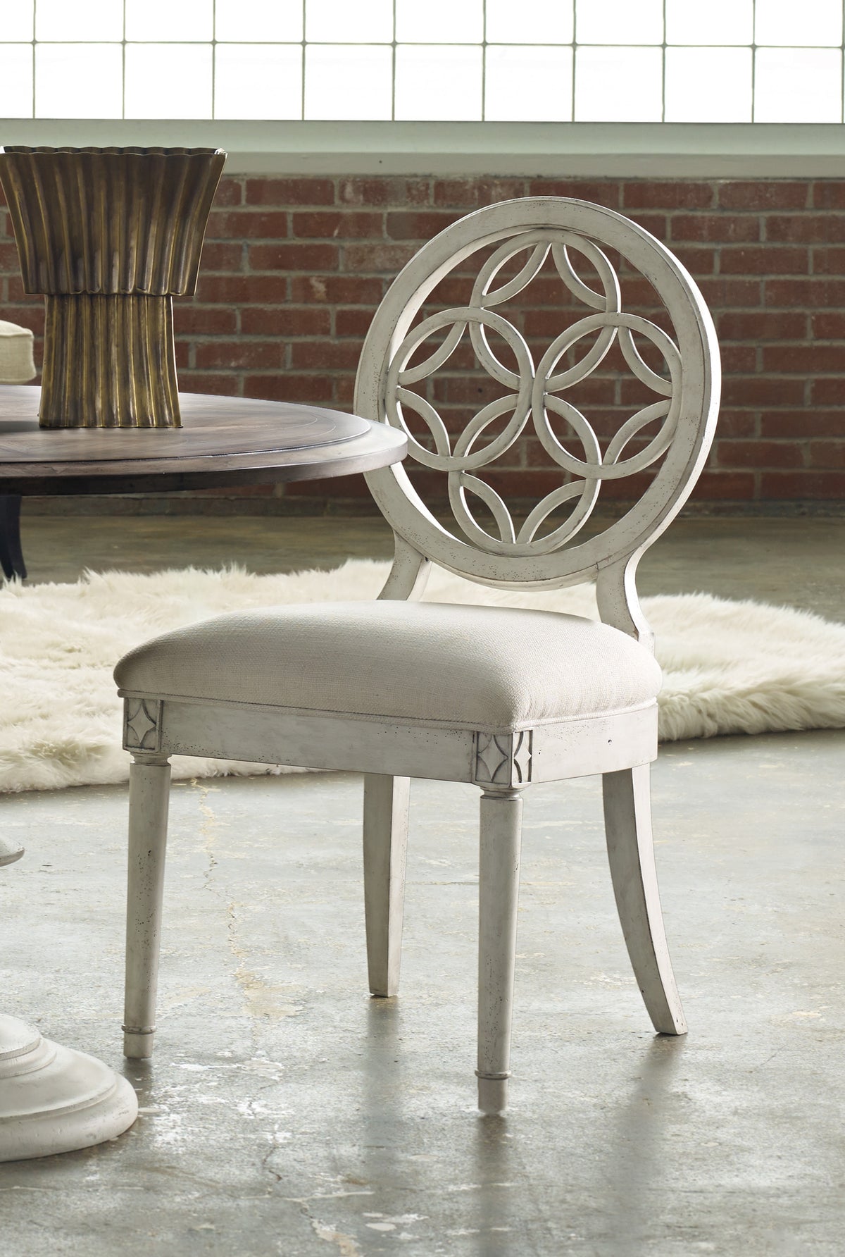 a white chair in front of a brick wall