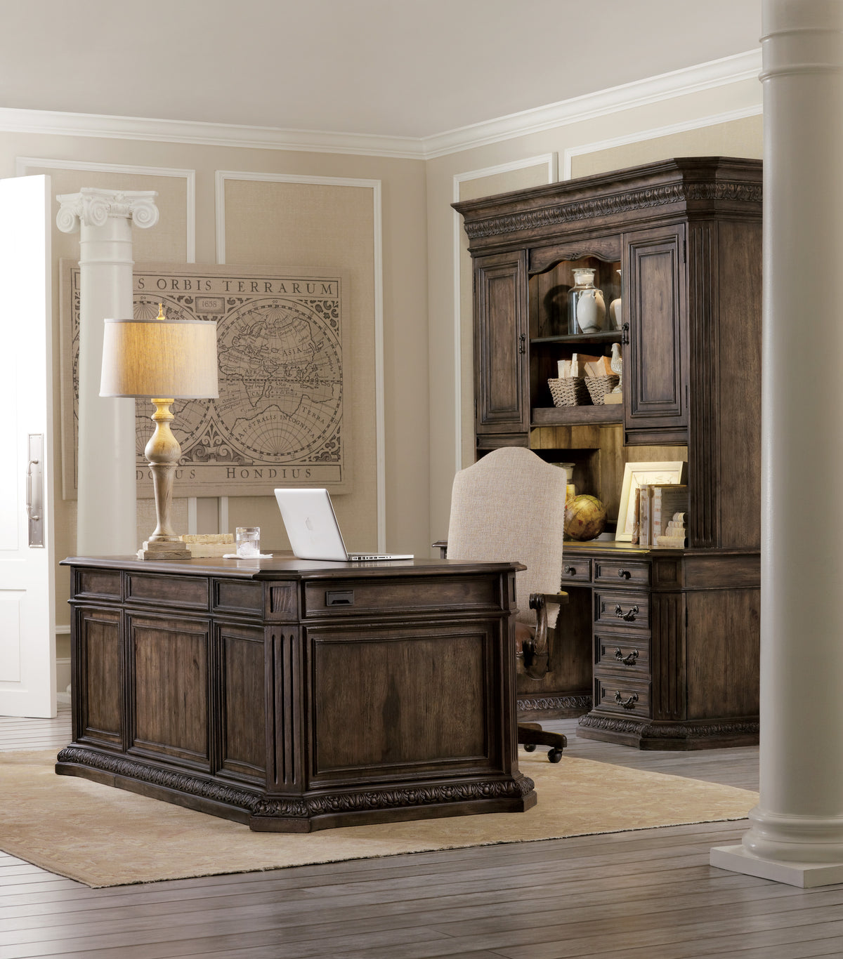 a desk in a room with a lamp and a bookcase