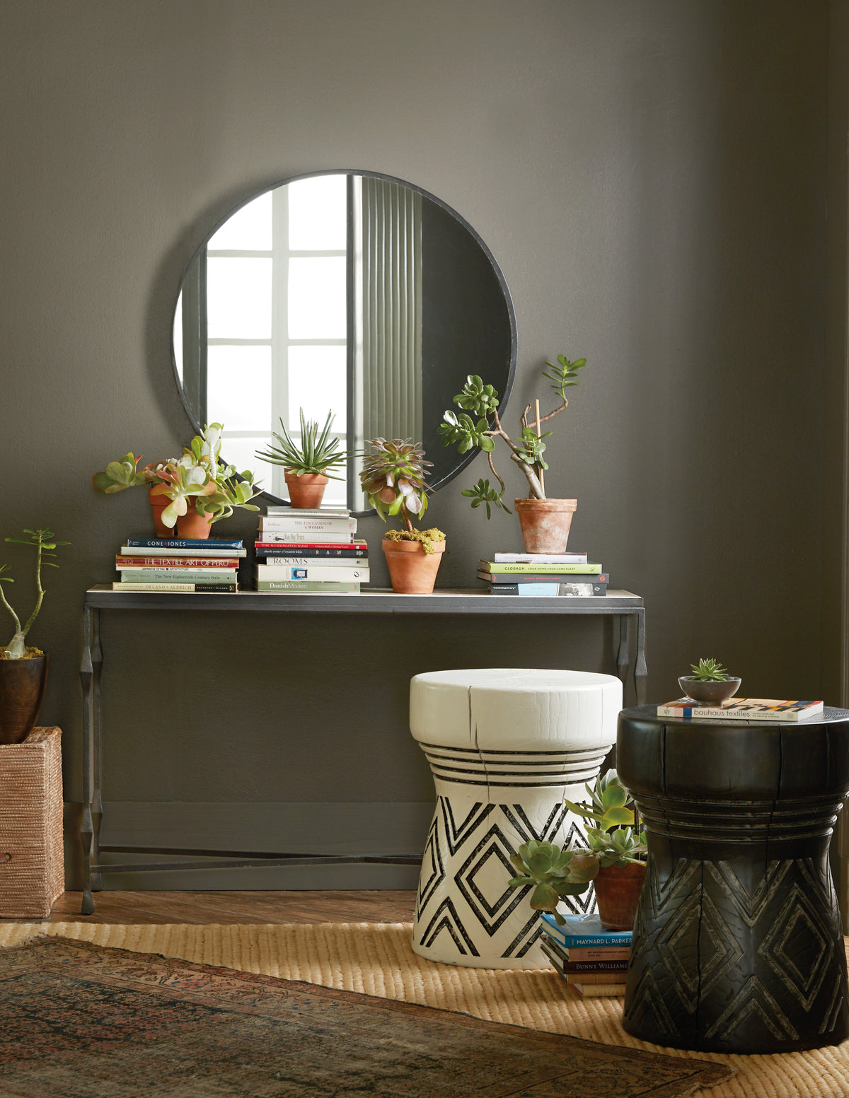 a round mirror above a table with potted plants