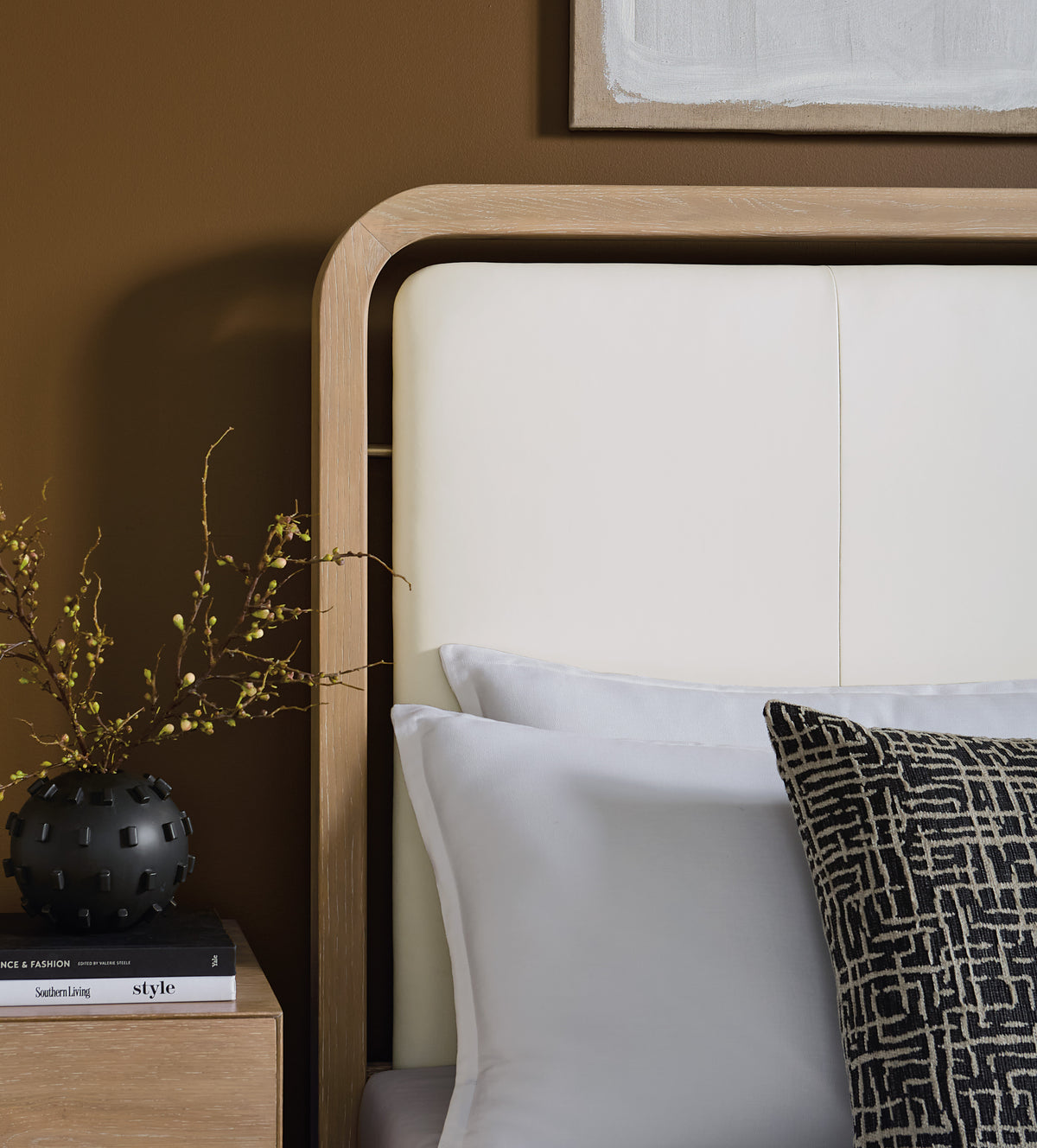 a white headboard with pillows and a vase of flowers