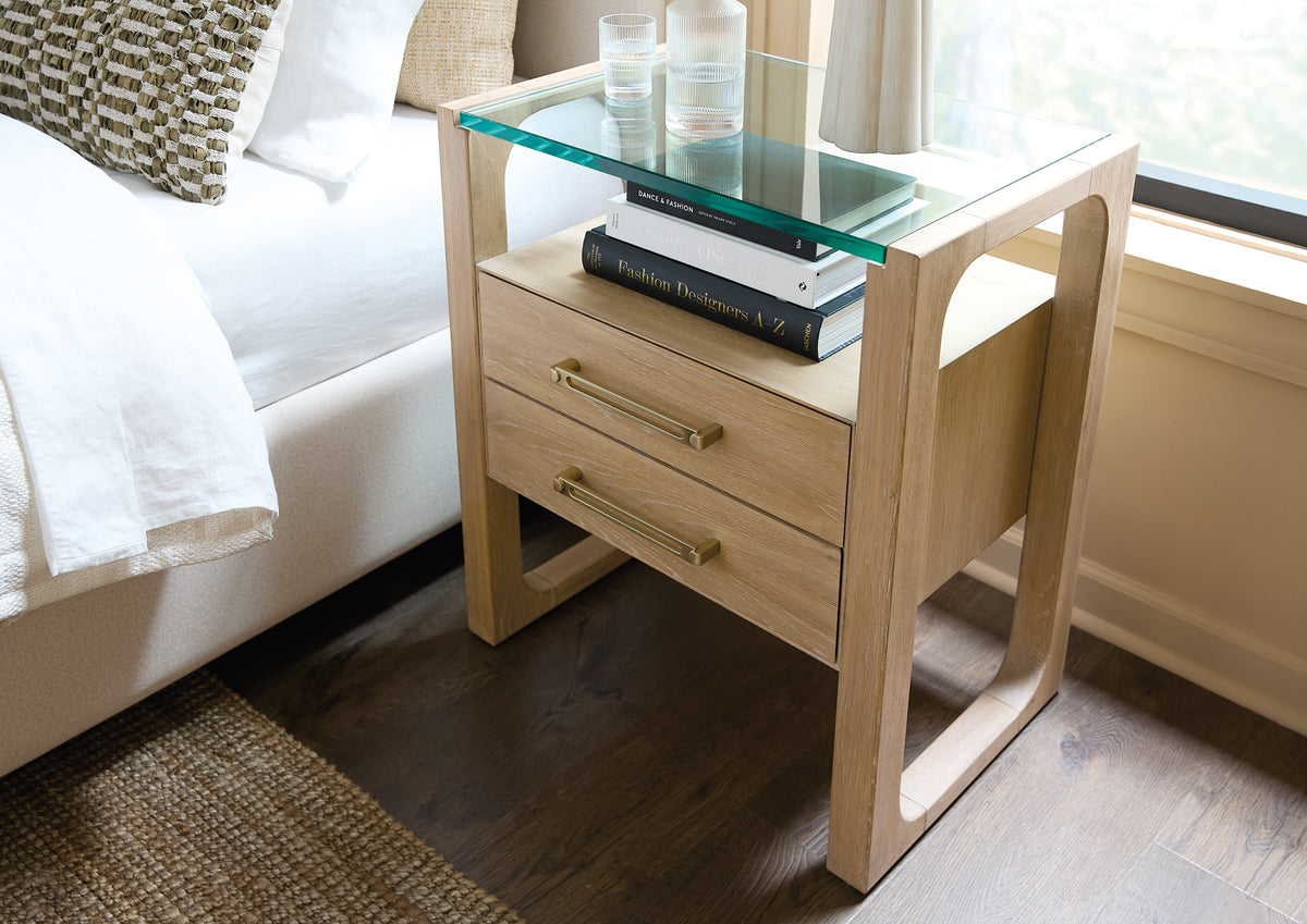 a nightstand with a glass top and books on top