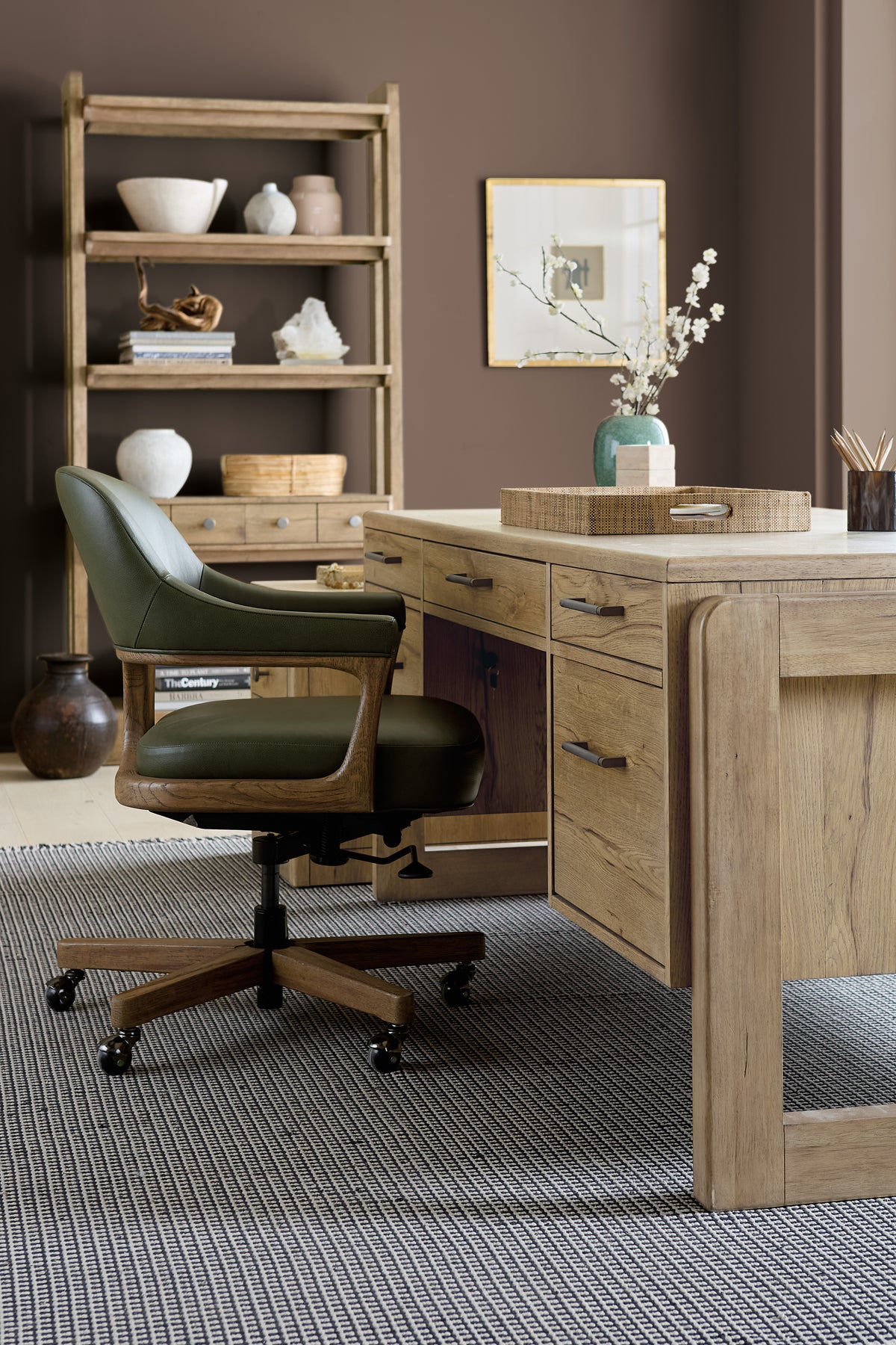 a desk with a chair and a vase of flowers on it