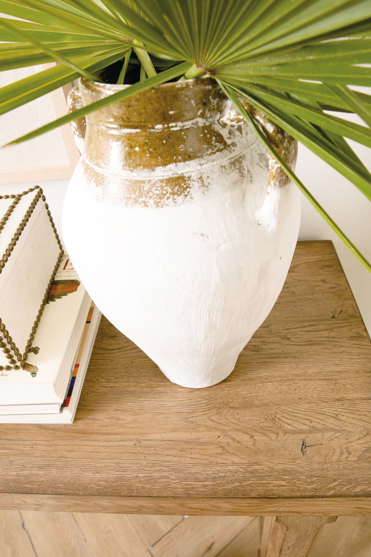 a white and gold vase with a green leaf
