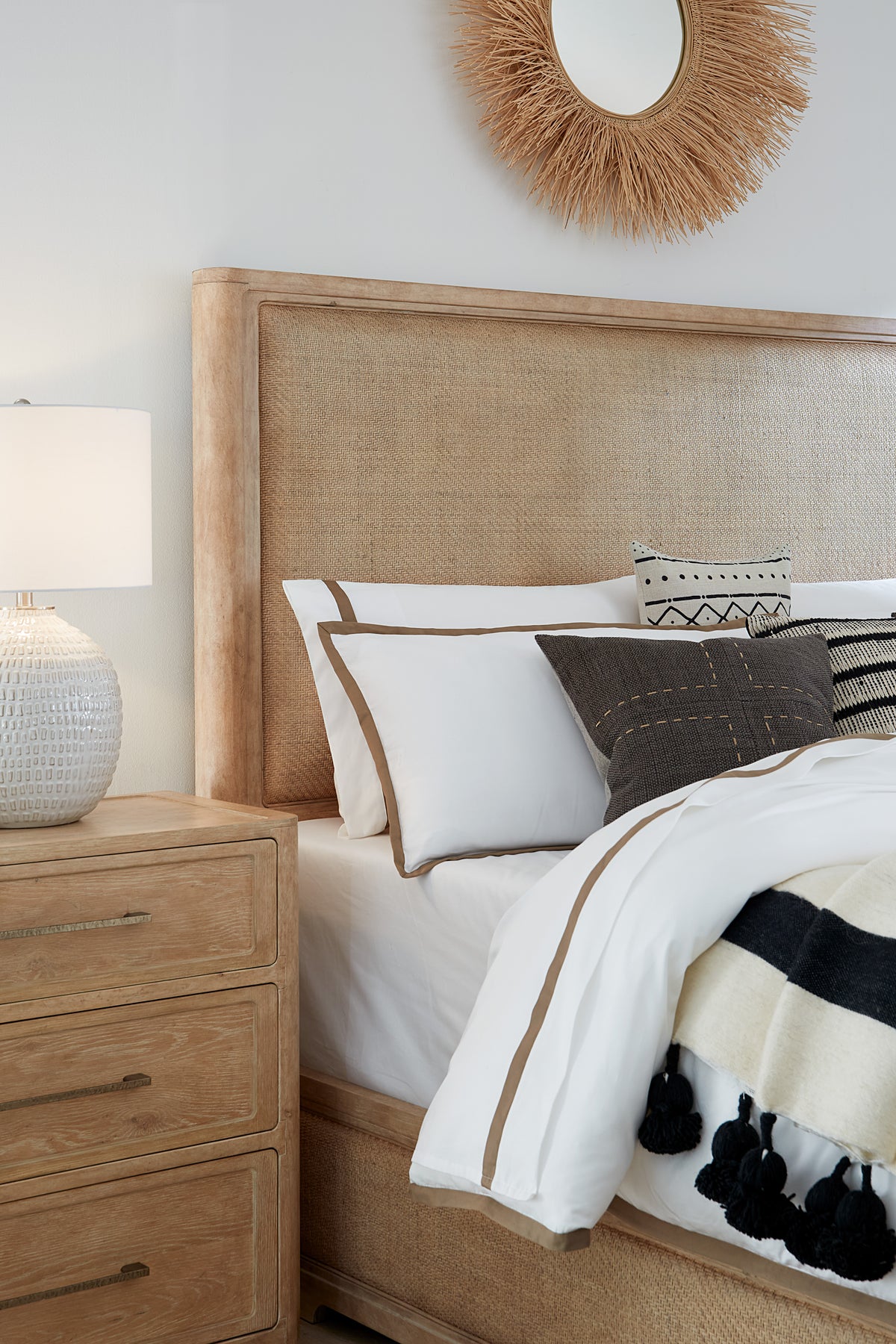 a bed with a rattan headboard and a lamp
