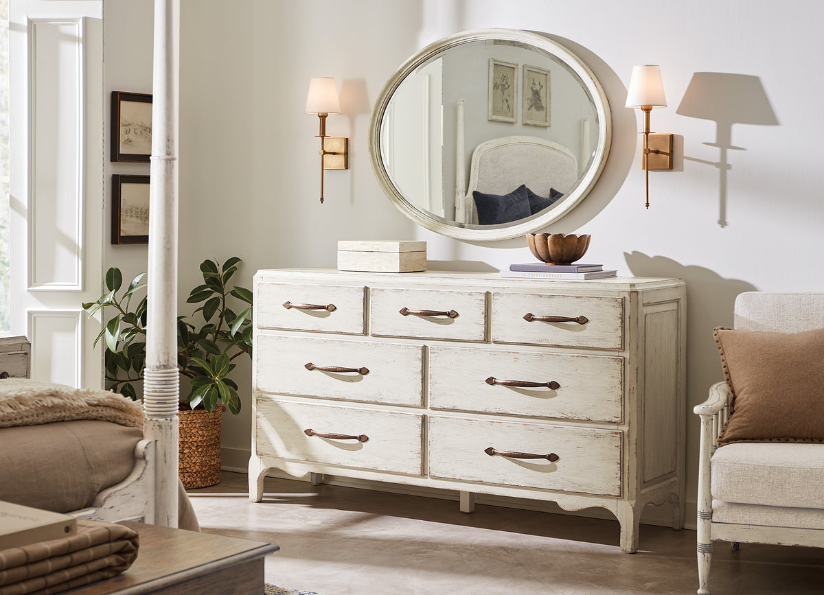 a white dresser with a round mirror above it