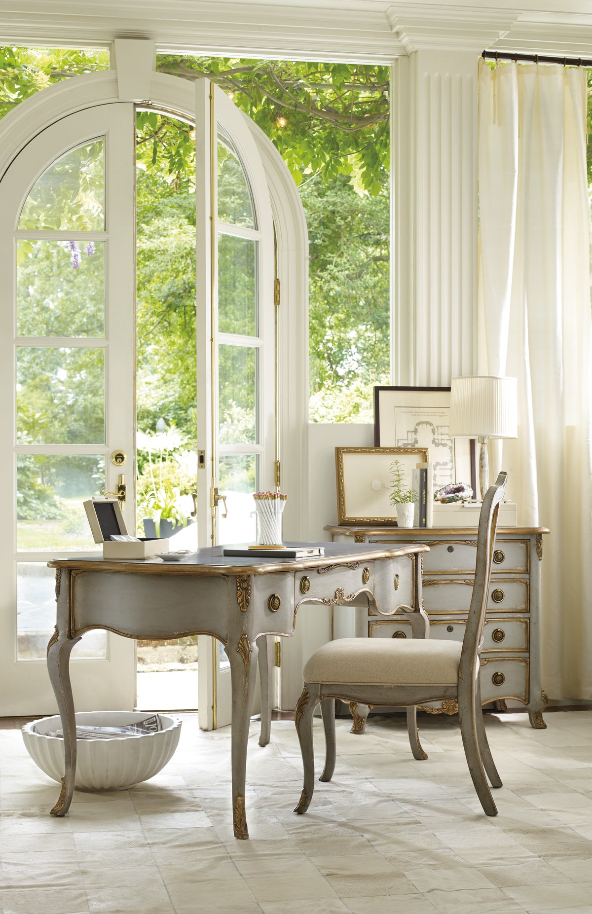 a desk in a room with windows and a chair