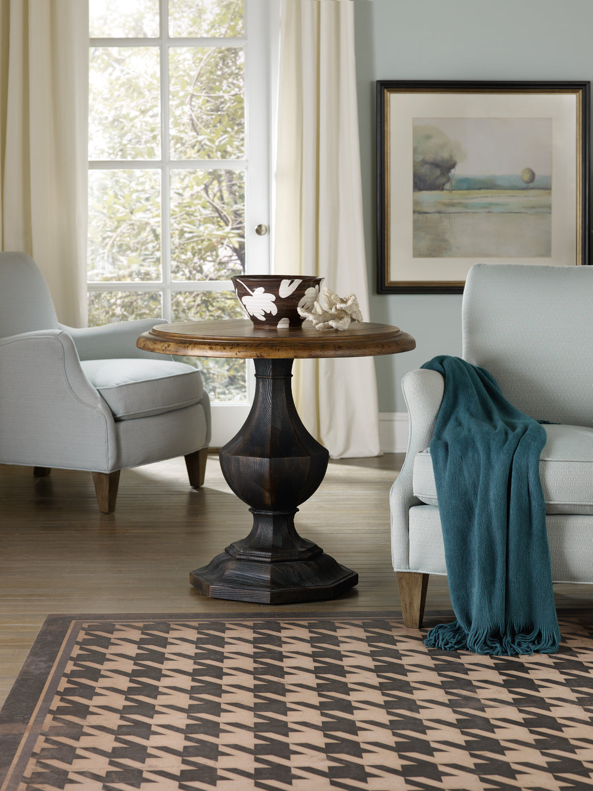 a table with a bowl on top and a chair in front of a window