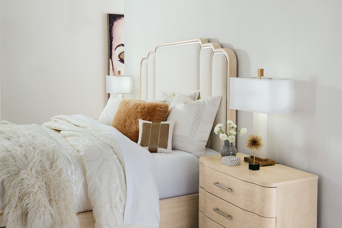 a bed with a white headboard and a lamp