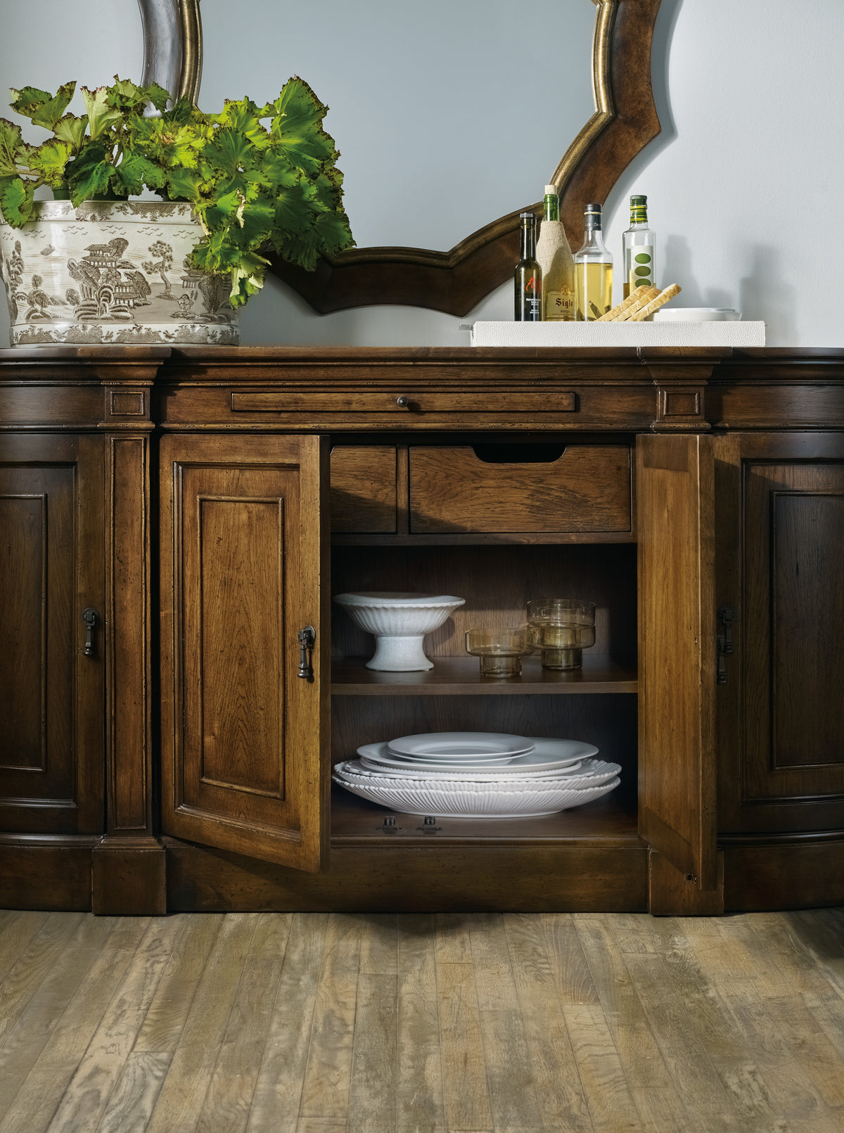 a wooden cabinet with plates and a plant on top