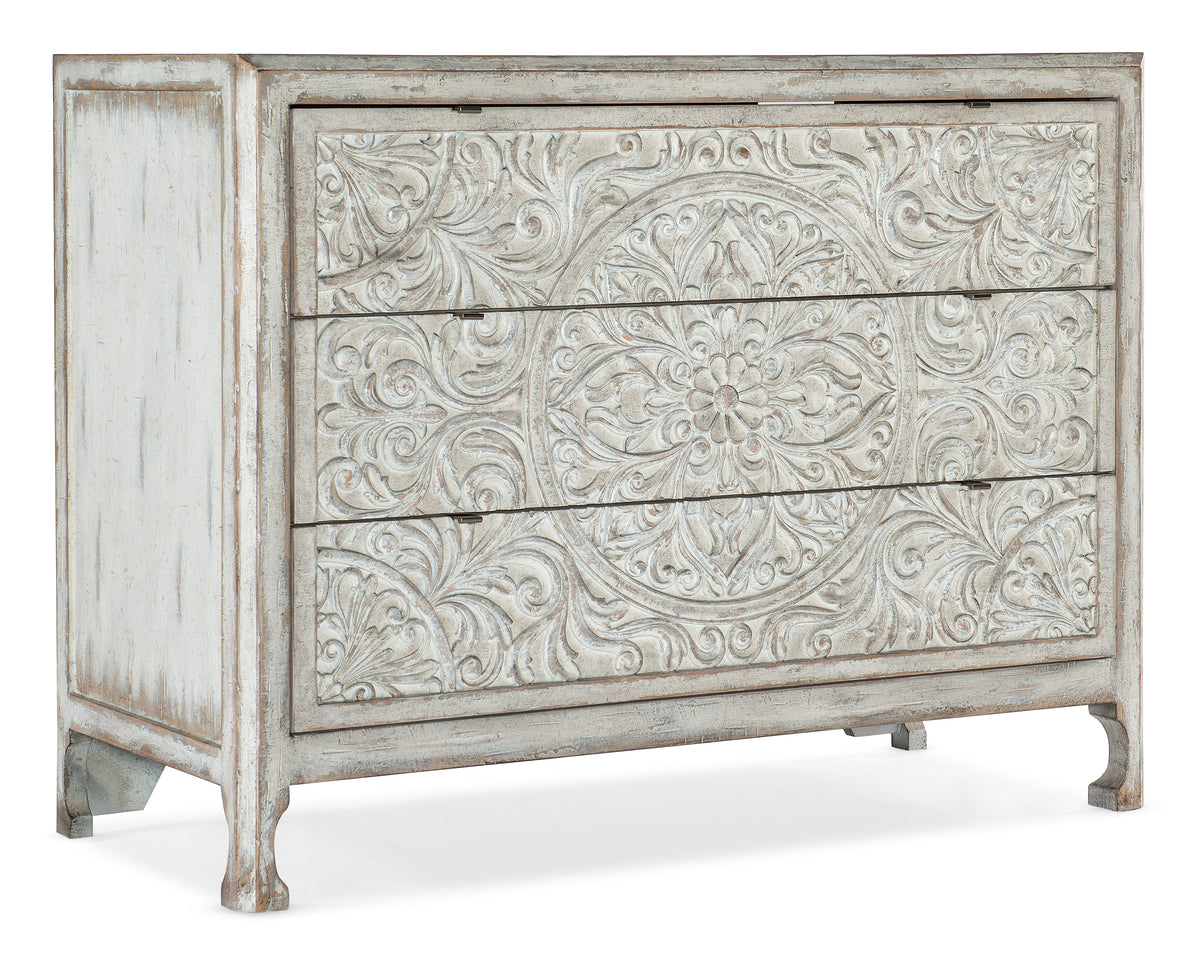 a white dresser with carved designs